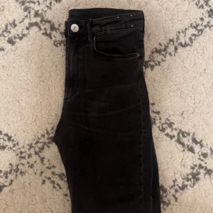 Svarta raka jeans - Svarta jeans med raka ben och klassisk femficksdesign. Byxorna har en silverfärgad knapp och dragkedja i gylfen. Passar perfekt till en avslappnad stil och är lätta att matcha med olika toppar.