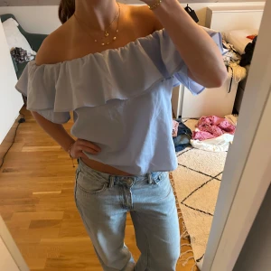 Ljusblå volangtopp - Säljer en ljusblå offshoulder topp med volang. Storlek 34