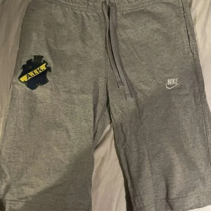 Grå mjukisbyxor från Nike med AIK-märke - Grå mjukisbyxor från Nike med dragsko i midjan och AIK-märke på vänster ben. Byxorna har en bakficka