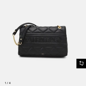 Svart  axelväska från Valentino -  svart quiltad axelväska från Valentino med kedjerem i guld och tydlig logga framtill. Väskan har en elegant design och passar till nästan allt 