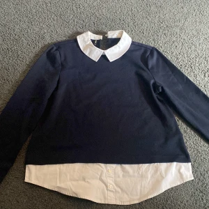 Mörkblå tröja med vit krage och skjortdetalj från Only  - Säljer en mörkblå långärmad tröja från Only med vit skjortkrage och vit nederkant. Väldigt fin men kommer inte till användning.                               Storlek S.