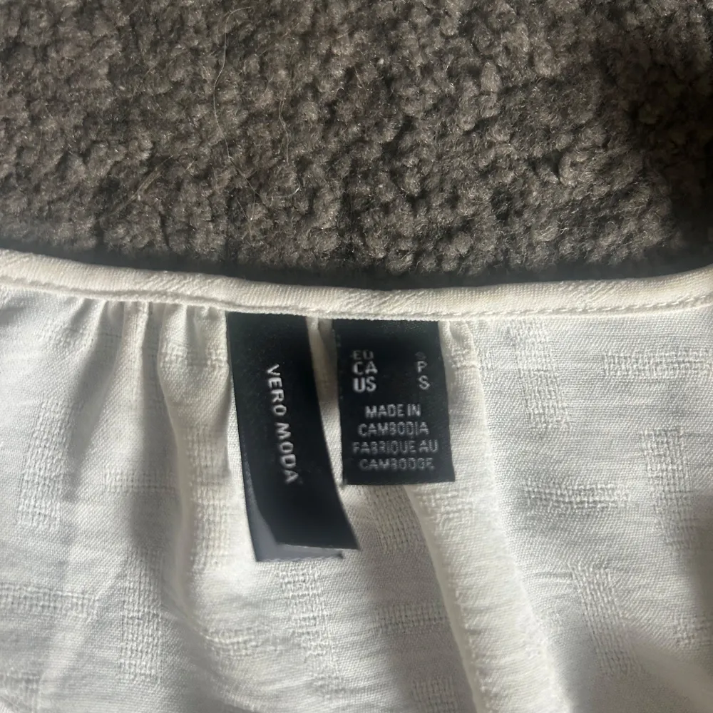 Säljer en stilren vit blus från Vero Moda med v-ringning och långa ärmar. Blusen har knappar vid ärmsluten. Perfekt för en fräsch och enkel look. Säljer för den är liten.. Puserot.