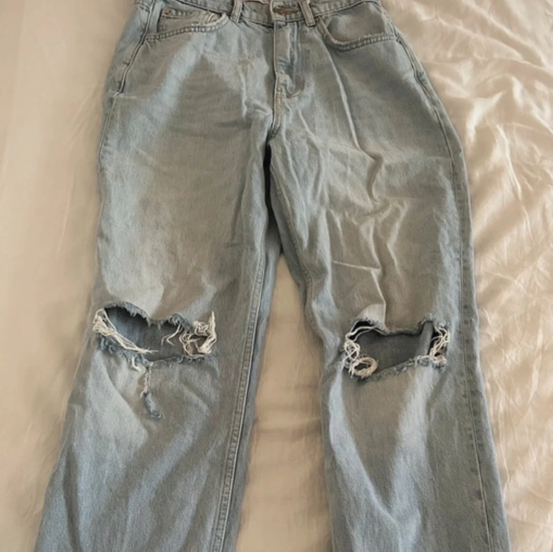 Ljusblå baggy jeans med hål på knäna 