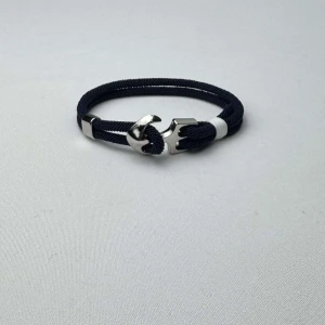 Marint armband med ankare - Snyggt armband i marinblått rep med ett silverfärgat ankare som lås. Perfekt accessoar för en stilren look. Helt sprillans nytt och armbandet kommer även med en smyckespåse till.