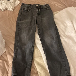 Svarta jeansbyxor med dragkedja - Säljer ett par svarta jeansbyxor i klassisk modell med fem fickor, dragkedja och knapp framtill. Byxorna har raka ben och en något tvättad look,lätta att sätta på sig sköna och mjuka 