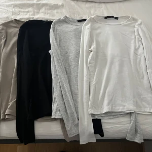 Fyra långärmade basic tröjor från Lager 157 - Säljer ett paket med fyra långärmade basic tröjor i olika färger: beige, svart, ljusgrå och vit. Alla har rund hals, lager 157, storlek Xs