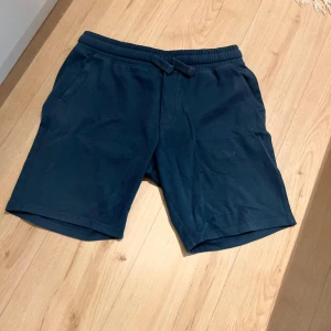 Blå shorts med snörning från Jachs - Mörkblå shorts från Jachs New York i mjukt bomullsmaterial. De har elastisk midja med snörning och två sidofickor. Perfekta för chill dagar och har en clean, enkel look som funkar till t-shirt eller hoodie.