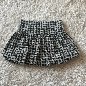 Rutig kortkjol från Zara i svart och vitt - Helt ny supersnygg kortkjol från Zara i svart och vitt med rutigt mönster i storlek S, perfekt till höst! Säljer då den är för liten för mig💝 OBS! Den är mycket liten i storleken och skulle snarare säga att den är en XS, lappen på kjolen har även lossnat på ena sidan - men inget slitage man ser utåt såklart då den är helt ny! 