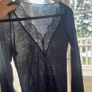 Intimissimi tröja  - Supersnygg svart långärmad topp från intimissimi med djup v-ringning och breda spetsdetaljer längs halsringningen. Tunn och lätt i materialet, perfekt för lager-på-lager eller som statement-piece. Sitter snyggt och känns riktigt lyxig.