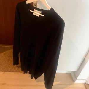 Svart v-ringad tröja  - Svart v-ringad tröja  i mjuk bomull. Klassisk och stilren design med långärmade ärmar och normal passform. Perfekt att matcha med jeans eller chinos för en clean look.