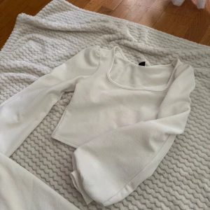 Vit croppad topp med puffärm - Säljer en vit croppad topp med långa puffärmar och fyrkantig ringning. Toppen har en stilren och enkel design som ger en trendig vibe. Perfekt att matcha med både jeans och kjol för en snygg look.