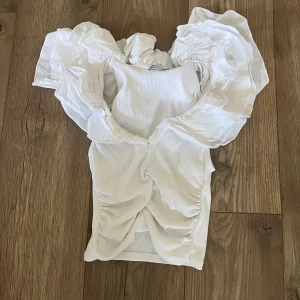 Vit volangtopp  - vit topp från Zara med stora volanger runt axlarna och djup urringning. Kommer inte till använding inga defekter. Storlek m men mer som en xs/s