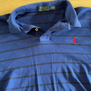 Blå randig pikétröja från Polo Ralph Lauren - Snygg randig blå långärmad pikétröja från Polo Ralph Lauren. Plagget är i använt skick men inga specifika defekter. Storleken är L men passar även större M. Fråga vid eventuella frågor🙌