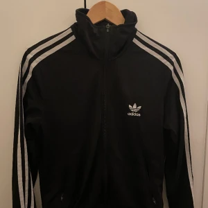 Adidas kofta - Svart adidas kofta, står strl 42 men passaren mest på S/M om man vill ha den tajt så är det nog 42 som gäller