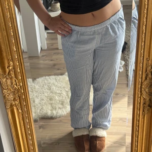 Randiga blåvita linnebyxor - Säljer ett par chill blåvita linnebyxor med smala ränder och elastisk midja. Byxorna har rak passform och är perfekta för en avslappnad stil. Superlätta och luftiga, passar perfekt till sommaren eller när du bara vill vara bekväm.