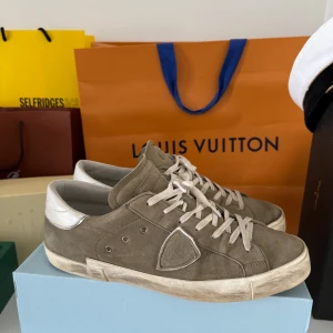 Philippe Model sneakers  - Snygga sneakers från Philippe Model i mocka med vita detaljer och snörning. Skorna har en klassisk låg siluett, vit platt sula och rund tå. Perfekta för dig som gillar stilrena och trendiga sneakers med premiumkänsla.