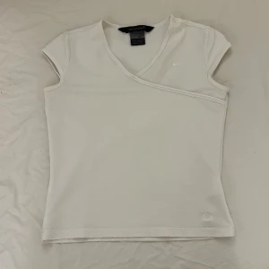 Jättesnygg träningströja från Nike  - Supersnygg vit träningströja från Nike med korta ärmar och diskret logga på bröstet. Toppen har en unik struktur med bikakemönstrad mesh. Passa e jättebra till att gymma, springa och yoga m.m. Säljer då den är för liten.