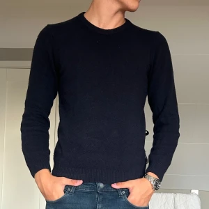 Mörkblå tröja från Casual Friday - Säljer en stilren mörkblå tröja från Frida Aasen. Tröjan har en klassisk rund hals och långa ärmar, perfekt för kyligare dagar. Den är tillverkad i ett mjukt material som ger en bekväm passform. Passar utmärkt till både jeans och kjol.