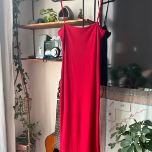 Röd långklänning med smala axelband - Säljer en snygg röd långklänning med smala axelband och rak halsringning. 