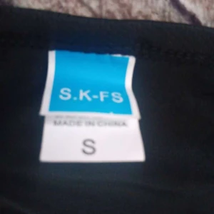 Vit t-shirt från S.K-FS, storlek S - En clean vit t-shirt från S.K-FS i storlek S. Klassisk rund hals och korta ärmar, perfekt för chill dagar. Materialet känns mjukt och lätt, troligtvis bomull eller polyester. Enkel och stilren utan mönster eller detaljer, passar till allt.