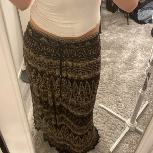 Svart och beige mönstrad långkjol - Super snygg långkjol i svart och beige med snyggt etnoinspirerat mönster. Kjolen har resår och snörning i midjan för perfekt passform. 