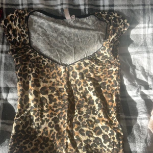 Leopardmönstrad topp med v-ringning - Cool topp i leopardmönster med v-ringad hals och korta ärmar. Tunt och mjukt material som känns skönt mot huden. Perfekt för dig som vill sticka ut med ett djurmönster och en snygg passform.