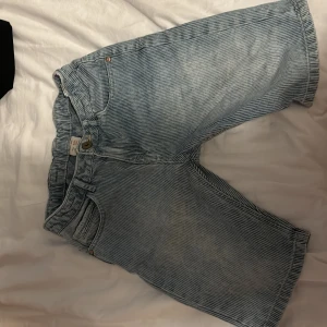 Randiga jeansshorts från Zara  - Snygga blå- och vitrandiga jeansshorts från Zara  med klassisk femficksdesign och elastisk midja. Perfekta för sommardagar, tillverkade i slitstarkt jeanstyg. Passar dig som gillar en avslappnad och cool stil.