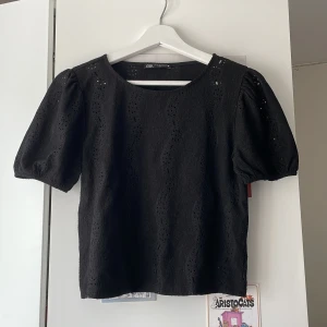 Svart blus med puffärm från Zara - Supersöt svart blus från Zara med korta puffärmar. Blusen har rund halsringning och är gjord i ett lätt, strukturerat tyg som känns luftigt. Har små trådar som hänger på vänster armen, men annars i ett bra skick❤️