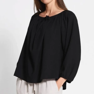 Svart blus med knytning - Svart blus med avslappnad passform och rundad halsringning med knytband. Långa, lite puffiga ärmar. Från lager 157. Borttagen prislapp men aldrig använd. Nypris 150 kr.