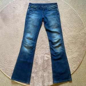 Lågmidjade utsvängda jeans - Snygga blå bootcut low waist jeans från vintage Wrangler med klassiska detaljer och logga på bakfickan. Jeansen har normal passform, fem fickor och är tillverkade i slitstarkt denim. Perfekta för dig som gillar retrovibbar och vill ha ett par jeans med lite utsvängda ben!😻Passar till varje plagg💋Innerben 80cm, midja 36cm, grenhöjd 19cm! Storlek W26 & L32, passar XS💕