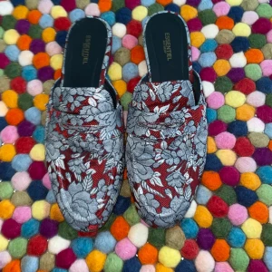 Blommiga loafers från Essentiel Antwerp - Unika loafers i röd och silvergrå bomull med blommigt mönster från Essentiel Antwerp. Skorna har öppen häl och platt sula, perfekt för dig som vill sticka ut med en cool och färgstark look. Snygg rund tå och bekväm passform.