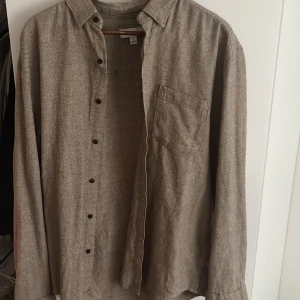 Beige skjorta i linne från Next - Snygg beige skjorta från Next i storlek L. Skjortan har en avslappnad passform, klassisk krage, bröstficka och knappar framtill. Tillverkad i ett grovt linnematerial som ger en cool och naturlig känsla. Perfekt att bära öppen över en t-shirt. Nypris 380 säljer för 110