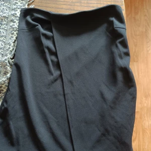 Svart topp från Bik Bok XS - Snygg svart topp från Bik Bok i storlek XS. Kjolen har en enkel och stilren design med rak passform. Materialet känns mjukt och har lite stretch, perfekt för att skapa en clean look. Passar dig som gillar minimalistisk stil.