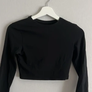 Svart, långärmad topp - Svart, croppad topp med långa ärmar och rund halsringning från Lager 157