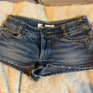 Blå jeansshorts från Vero Moda - Säljer ett par snygga blå jeansshorts från Vero Moda. De har en knapp och dragkedja framtill samt klassiska femficksdetaljer. Perfekta för sommardagar!