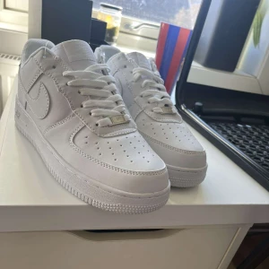 Vita Nike Air Force sneakers - Säljer ett par klassiska vita Nike Air Force sneakers. De har en stilren design med snörning och en robust sula. Perfekta för en casual look.