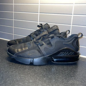 Svarta Nike Air Max sneakers  - Snygga svarta Nike Air Max Infinity sneakers med en modern design och bekväm passform. Skorna har en synlig Air Max-dämpning i hälen och är tillverkade i syntetmaterial med snörning för en säker passform. Perfekta för både träning och vardag.