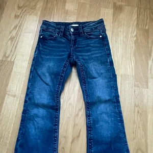 Blå jeans från Gina Tricot - Snygga blå jeans från Gina Tricot med klassisk femficksdesign och knappgylf. Utsvänga jeans 💓Säljer för att de blivit för små. Använda ett fåtal gånger🥰