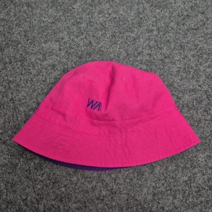 Rosa solhatt barn - Snygg rosa solhatt från Stadium med broderad logga framtill. Hatten är tillverkad i 100% bomull och har en lila insida. Perfekt för sommarens äventyr!