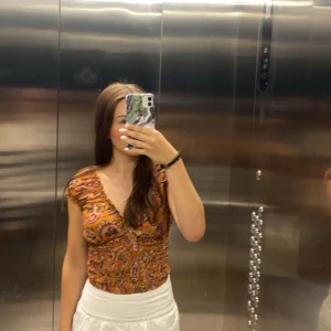 Sommartopp - Säljer en jättefin somrig topp från Gold & Silver med mönster i orange, rosa och svart. Storlek står som ”T1” men motsvarar S. Toppen har volangdetaljer och en smockad midja🧡