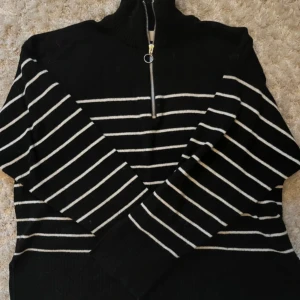 Svart och vit randig tröja med dragkedja - Säljer en svart tröja med vita ränder och dragkedja i halsen. Tröjan har långa ärmar och en hög krage. Slits i armar och midja🖤 köpt på gekås, märket Samsa 