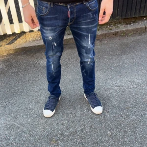 Dsq2 jeans  - Snygga mörkblå jeans med slitningar och en tight passform. De har en klassisk femficksdesign och en dragkedja. Perfekta för en avslappnad stil.