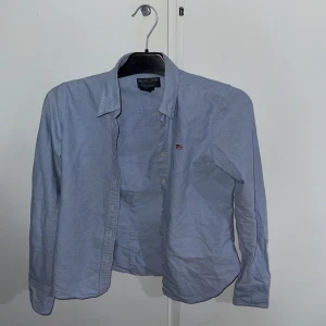Blå skjorta från Polo Jeans Company - Passar de i 148-156Snygg blå skjorta från Polo Jeans Company med broderad RL-logga på bröstet. Skjortan är tillverkad i 100% bomull och har långa ärmar samt knappar framtill. Perfekt för en stilren look. Nästan aldrig använd förutom på ett bröllop. Mycket bra skicke. Priset är inte hugget i sten