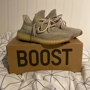 Adidas Yeezy Boost 350 V2 - Säljer ett par Adidas Yeezy Boost 350 V2 i en stilren beige färg. Skorna har en stickad ovandel med snörning och en bekväm Boost-sula. Perfekta för dig som vill ha både stil och komfort. Säljer pågrund av att dom blivit försmå!
