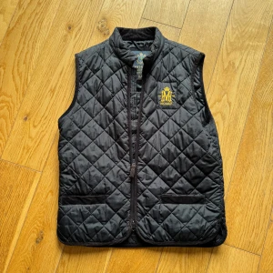 Svart quiltad väst från Morris - Snygg svart quiltad väst från Morris med dragkedja och broderad logga på bröstet. Perfekt för lager-på-lager under kyligare dagar men även till sommaren