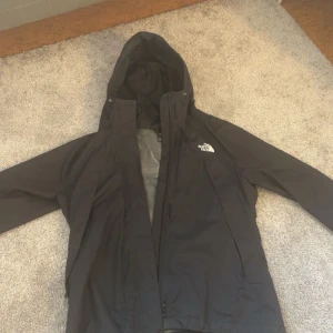 Svart regnjacka från The North Face - Säljer en svart regnjacka från The North Face i storlek S. Jackan har en justerbar huva och dragkedja framtill. Perfekt för regniga dagar och håller dig torr och bekväm. 🖤 Inköpt för 1,2k för ungefär ett år sen.