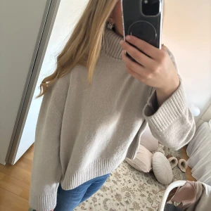 Beige stickad polotröja - Säljer en mysig beige stickad polotröja med ribbade detaljer vid krage, ärmslut och nederkant. Perfekt för kyliga dagar och ger en stilren look. Passar bra till jeans eller kjol. 🧶