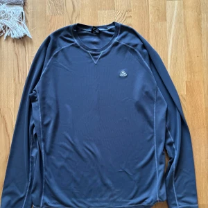 långärmad tröja från Nike ACG - Säljer en  långärmad tröja från Nike ACG. Tröjan har en rund halsringning och ett diskret ACG-märke på bröstet. Perfekt för utomhusaktiviteter eller som ett lager under jackan. Skön och funktionell design.