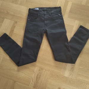 Svarta jeans från Replay Anbass - Snygga svarta jeans från Replay med en klassisk femficksdesign. De har en knappgylf och bälteshällor, vilket gör dem perfekta för en stilren look. Passformen är slim.