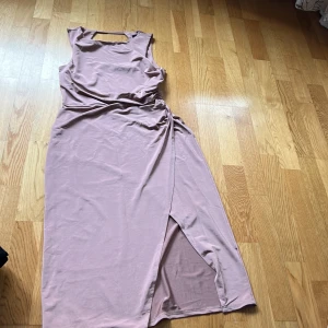 Rosa klänning från Topshop - Säljer en elegant rosa klänning från Topshop med en stilren design. Klänningen har en slits och är ärmlös, vilket ger en chic look. Perfekt för sommarens tillfällen. Lite glatt material. Töjbart och mycket bekväm. 